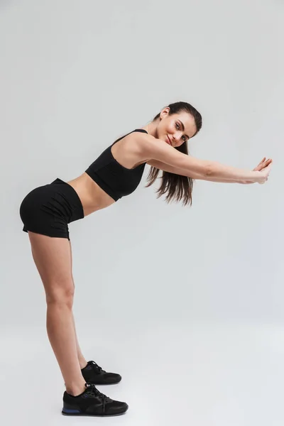 Piękny młody Sport fitness kobieta zrobić ćwiczenia izolowane na szarym tle ściany. — Zdjęcie stockowe
