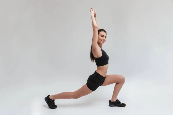 Bonita jovem esporte fitness mulher fazer exercícios isolados sobre fundo de parede cinza . — Fotografia de Stock