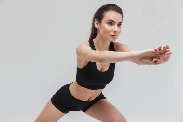 Bonita jovem esporte fitness mulher fazer exercícios isolados sobre fundo de parede cinza . — Fotografia de Stock