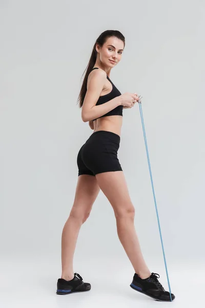 Piękna młoda kobieta Sport fitness zrobić ćwiczenia z wyposażeniem odizolowanym na szarym tle ściany. — Zdjęcie stockowe
