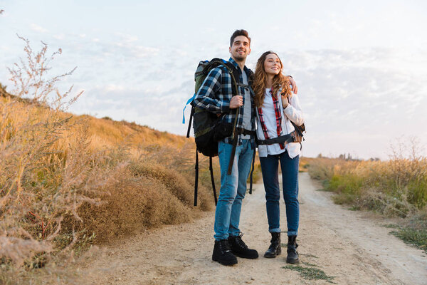 Happy young loving couple outside with backpack in free alternative vacation camping.