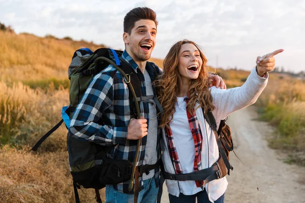 Vrolijk jong stel vervoert rugzakken samen wandelen — Stockfoto