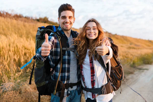 Vrolijk jong stel vervoert rugzakken samen wandelen — Stockfoto