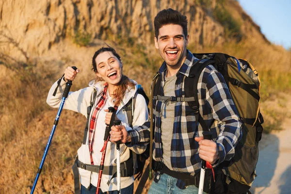 Vrolijk jong stel vervoert rugzakken samen wandelen — Stockfoto