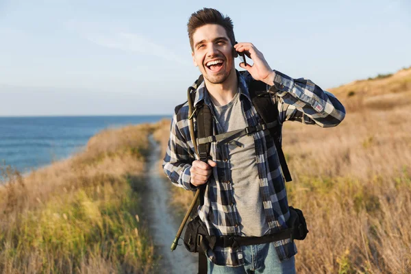Happy young man outside in free alternative vacation camping talking by mobile phone.