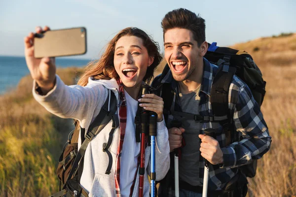 Jovem casal alegre carregando mochilas caminhando juntos — Fotografia de Stock