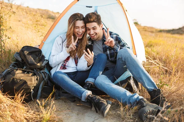 Cheerful young couple camping, sitting — Stock Photo, Image