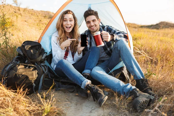 Gelukkig jong liefdevolle paar buiten in gratis alternatieve vakantie Camping drinken hete thee. — Stockfoto