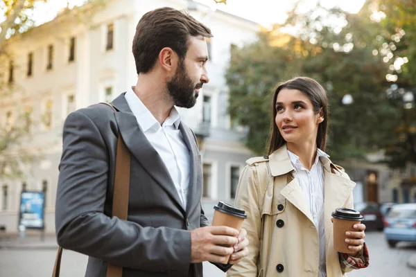 Photo of young office workers man and woman drinking takeaway coffee while walking on city street — Stock Photo, Image