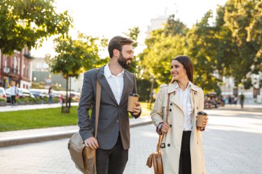 Şehir caddesinde yürürken paket kahve tutan sevimli ofis çalışanları nın erkek ve kadının fotoğrafı
