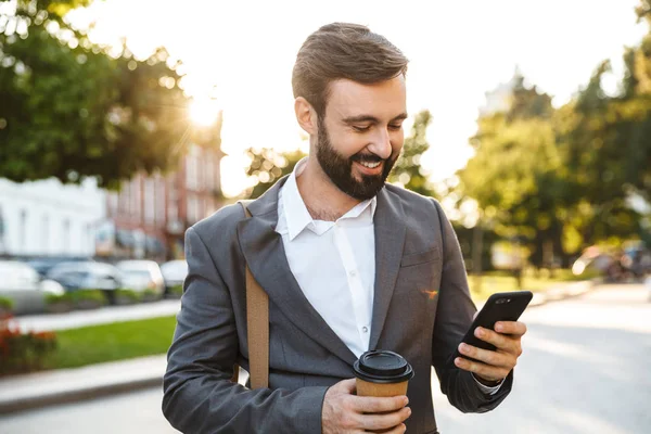 Ritratto di bell'uomo d'affari adulto in abito formale con caffè da asporto e smartphone all'aperto — Foto Stock