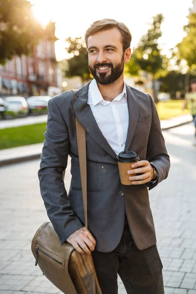 Portrait of caucasian adult businessman in formal suit holding takeaway coffee while walking through city street — Stock Photo, Image