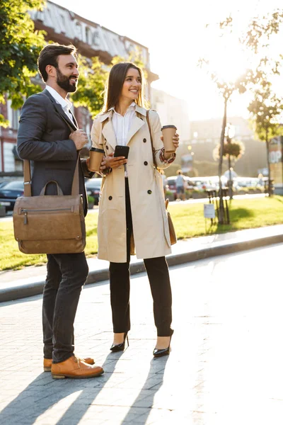 Porträt eines glücklichen Geschäftsmannes und einer Frau, die Kaffee zum Mitnehmen trinken und miteinander reden, während sie sich auf der Straße der Stadt treffen — Stockfoto