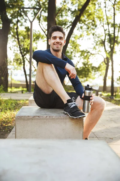 Portrét mladého atletického muže sedícího na lavičce — Stock fotografie
