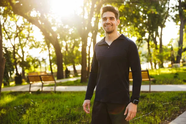 Bonito jovem esportes fitness homem de pé na natureza parque verde . — Fotografia de Stock