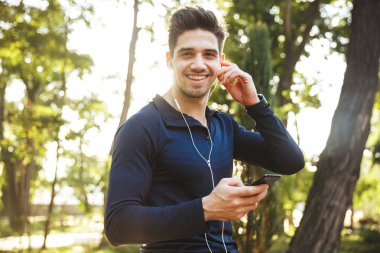 Kulaklıkla müzik dinleyen gülümseyen atletik adamın portresi