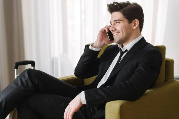 Homem bonito confiante vestindo terno sentado em poltrona — Fotografia de Stock