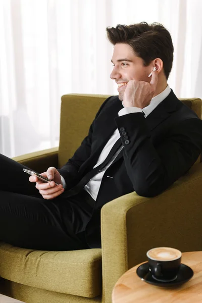 Koltukta oturan takım elbise giyen kendine güvenen yakışıklı adam — Stok fotoğraf