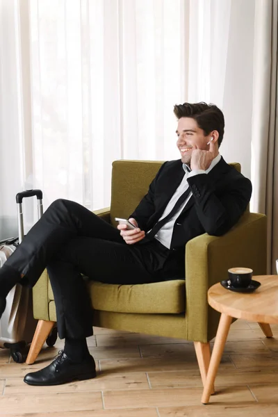 Un bel homme confiant portant un costume assis dans un fauteuil — Photo