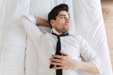 Otel dairesinde yatakta yatan kafkas sakallı işadamının tepesinden fotoğraf