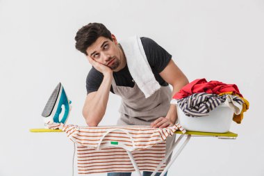 Demir ve beyaz duvar arka plan üzerinde izole giysiler ile yorgun sıkılmış genç ev kadını househusband.
