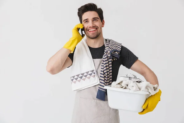 Photo of joyful young man wearing yellow rubber gloves using sma — Stock Photo, Image