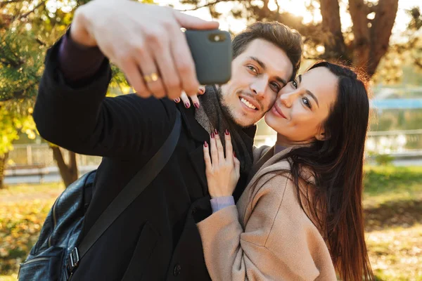 Piękny kochający para pozowanie chodzenie na dworze w Park natura brać selfie przez zdejmowany telefon. — Zdjęcie stockowe