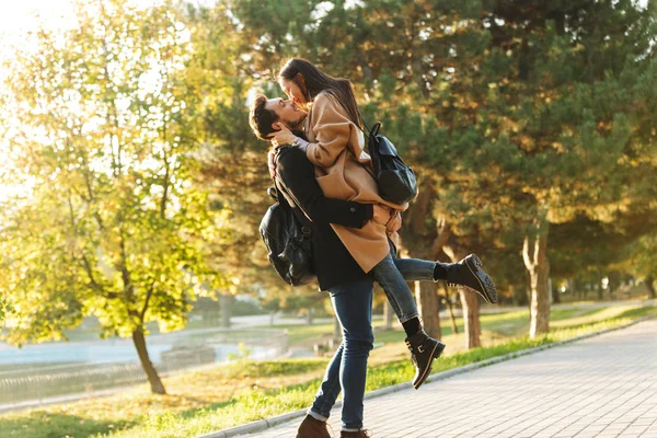 Happy young beautiful loving couple posing walking outdoors in park nature kissing. — Stock Photo, Image