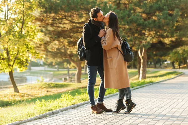 Happy young beautiful loving couple posing walking outdoors in park nature kissing. — Stock Photo, Image
