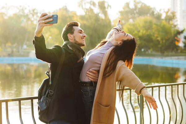 快乐 年轻 美丽的 爱 夫妇 冒充 走在 公园 自然 采取 自拍 通过 手机. — 图库照片