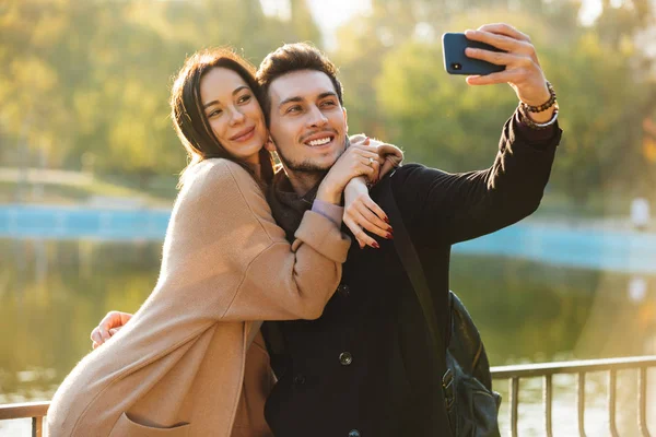 Jovens felizes belo casal amoroso posando andando ao ar livre no parque natureza tirar selfie por telefone móvel . — Fotografia de Stock