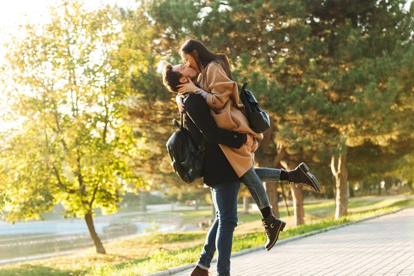 Glücklich junge schöne liebende Paar posiert zu Fuß im Freien im Park Natur küssen. — Stockfoto