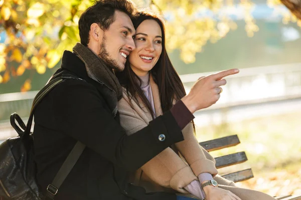 Jovens felizes belo casal amoroso posando andando ao ar livre no parque natureza sentado no banco . — Fotografia de Stock