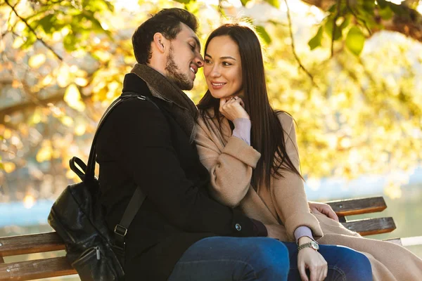 快乐年轻美丽的爱夫妇摆姿势走在公园自然坐在长凳上. — 图库照片
