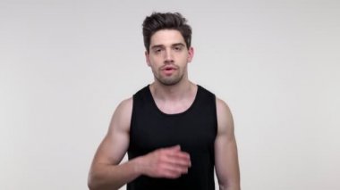 Üzgün genç sakallı sportif adam siyah arka plan izole üzerinde kameraya bakarken yorucu oluyor