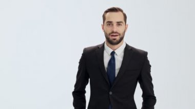 Siyah takım elbise ve mavi kravat neşeli genç işadamı seviniyor ve gri arka plan izole üzerinde kameraya bakarken kazanan jest yaparken