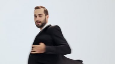 Siyah takım elbise li ve mavi kravatlı neşeli genç işadamı dans ediyor gibi dönüyor ve gri arka plan üzerinde kameraya gülümsüyor izole