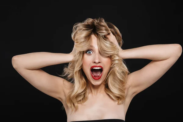 Mujer rubia joven conmocionada con labios rojos maquillaje brillante posando aislado sobre fondo de pared negro . —  Fotos de Stock