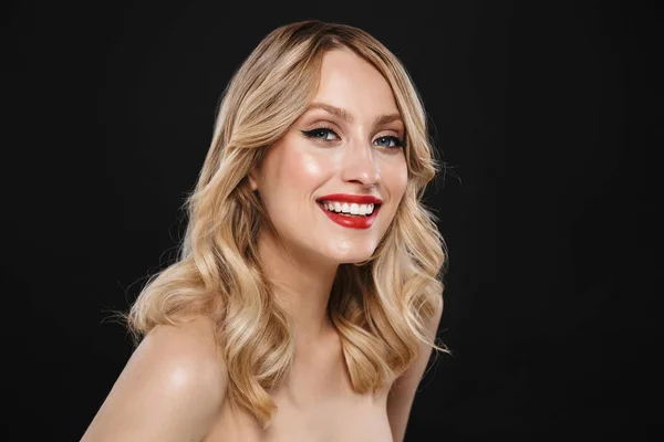 Glücklich fröhliche blonde Frau mit hellem Make-up rote Lippen posieren isoliert über schwarzen Wandhintergrund. — Stockfoto