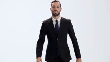 Siyah takım elbise ve mavi kravat ciddi genç işadamı kameraya yürüme ve izole gri arka plan üzerinde tökezledi