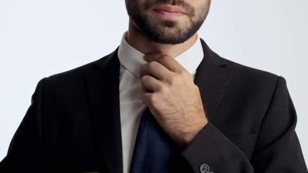 黒いスーツと青いネクタイで疲れた若いビジネスマンのトリミングされたビューは 彼のシャツのボタンを外し 孤立した灰色の背景の上にネクタイを脱ぐ — ストック動画