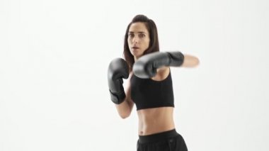 Beyaz arka plan izole üzerinde kameraya bakarken siyah eldiven boks ile siyah spor giyim aktif sevimli sportif esmer kadın