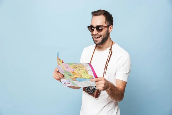 Bello giovane turista posa con mappa isolata su sfondo muro blu . — Foto Stock