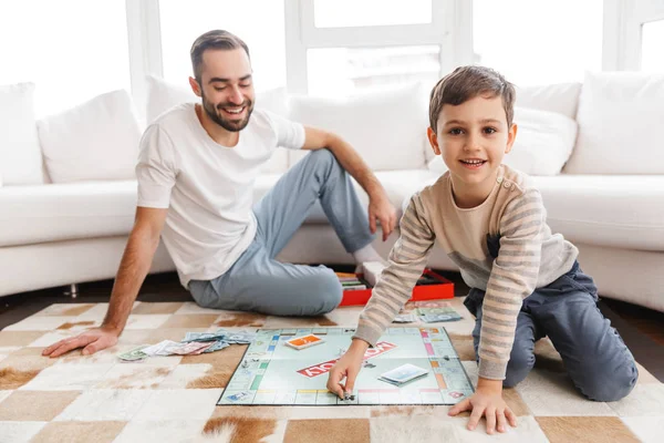 Jovem pai alegre jogando monopólio — Fotografia de Stock