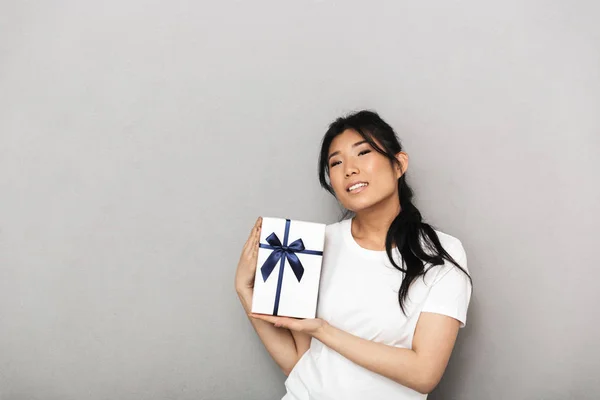 Asiatische schöne junge Frau posiert isoliert über graue Wand Hintergrund in der Nähe Geschenk-Box. — Stockfoto