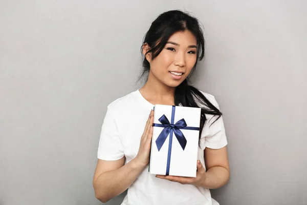 Asiatische schöne junge Frau posiert isoliert über graue Wand Hintergrund in der Nähe Geschenk-Box. — Stockfoto