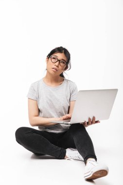 Asya güzel genç kadın poz üzerinde izole beyaz duvar arka plan tutan dizüstü bilgisayar kullanarak.