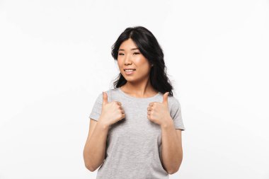 Asyalı güzel genç kadın beyaz duvar arka plan gösteren başparmak yukarı jest üzerinde izole poz.