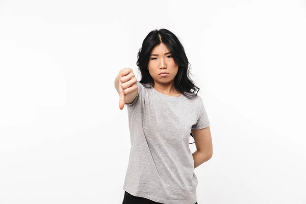 Азіатський сумно красива молода жінка позує ізольовані над білою стіною фону показуючи пальці вниз. — стокове фото
