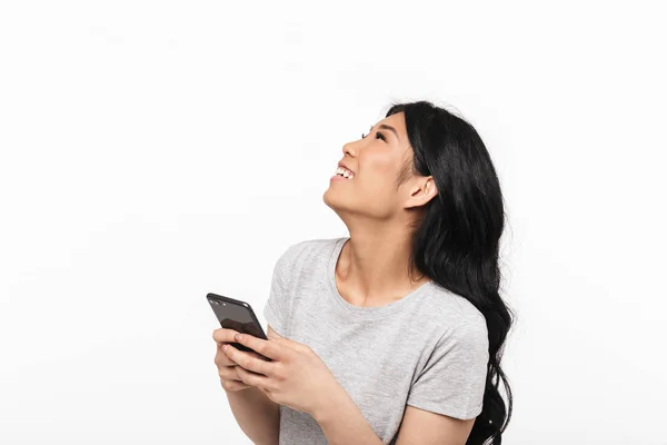 Азіатські красива молода жінка позує ізольовані над білим фоном стіни за допомогою мобільного телефону. — стокове фото